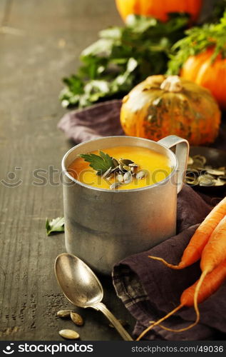 Pumpkin soup in a metal pot on a wooden surface