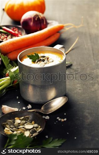 Pumpkin soup in a metal pot on a wooden surface