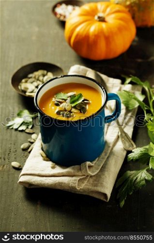 Pumpkin soup in a metal pot on a wooden surface, close up. Pumpkin soup in a metal pot on a wooden surface and ingredients