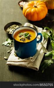Pumpkin soup in a metal pot on a wooden surface, close up. Pumpkin soup in a metal pot on a wooden surface and ingredients