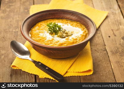 Pumpkin soup in clay bowl with spoon on the table