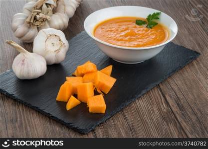 Pumpkin soup on white wood background.