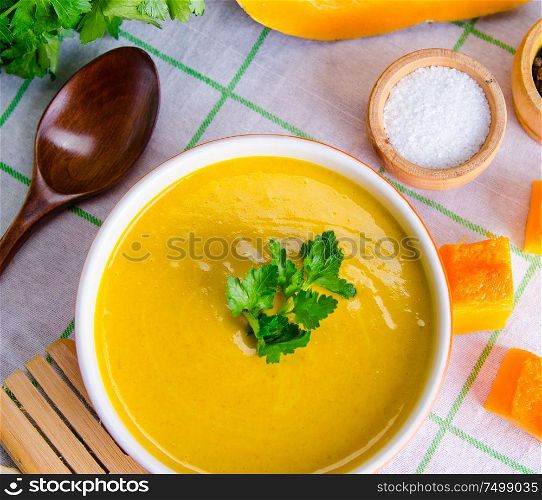 Pumpkin soup served on the table in bowl. The pumpkin soup served on the table in bowl