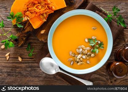 Pumpkin soup. Vegetarian soup with pumpkin seeds in bowl on wooden table, top view
