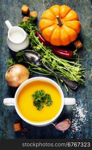Pumpkin soup with fresh ingredients on wooden board