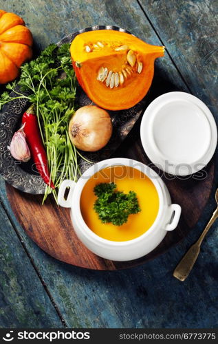 Pumpkin soup with fresh ingredients on wooden board
