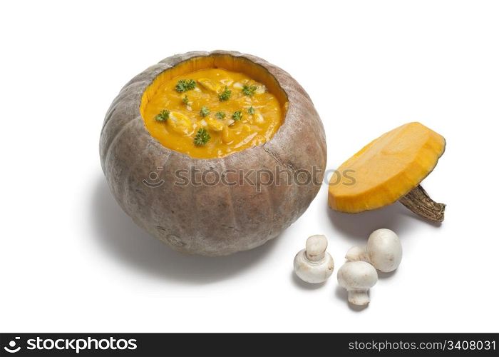 Pumpkin soup with mushrooms served in a Hubbard Squash on white background