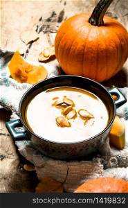 pumpkin soup with seeds on the old fabric. On wooden background.. pumpkin soup with seeds on the old fabric.