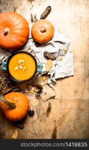 pumpkin soup with seeds on the old fabric. On wooden background.. pumpkin soup with seeds on the old fabric.