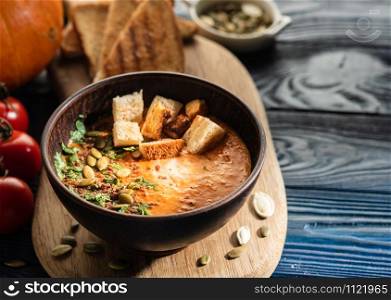 Pumpkin soup with sour cream and pumpkin seeds on a wooden table