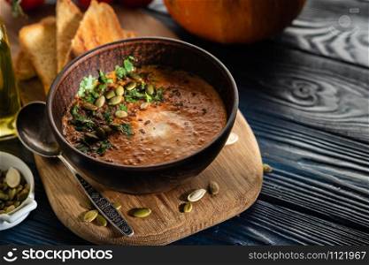 Pumpkin soup with sour cream and pumpkin seeds on a wooden table