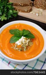 Pumpkin soup with sour cream sauce flavored pumpkin seeds and mint