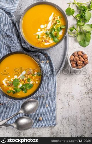 Pumpkin soup with watercress on table. Seasonal autumn food - Spicy pumpkin soup in bowl.