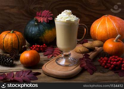 Pumpkin spice coffee latte with whipped cream, cookies, fall leaves, fir cones, rowan berries