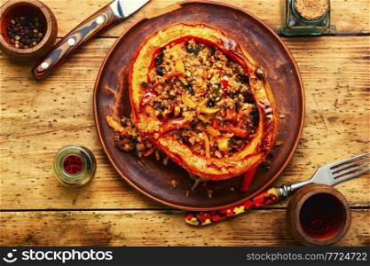 Pumpkin stuffed minced meat, vegetables and quinoa. Autumn traditional food on old wooden background. Baked squash with minced meat and quinoa