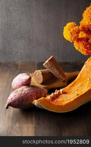 Pumpkin, Sweet potatos Camote and unprocessed sugar cane Piloncillo on rustic wooden table. Raw Ingredients for mexican traditional dessert for dia de muertos.