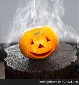 Pumpkin that laughs on a charred stub in smoke. Scenery for Halloween holiday.