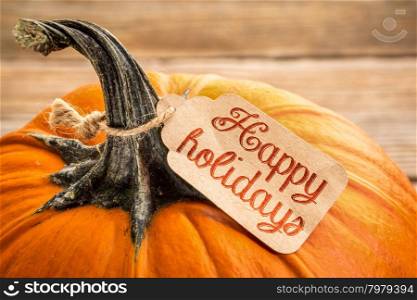pumpkin with a Happy Holidays price tag - Halloween or Thanksgiving holiday season concept