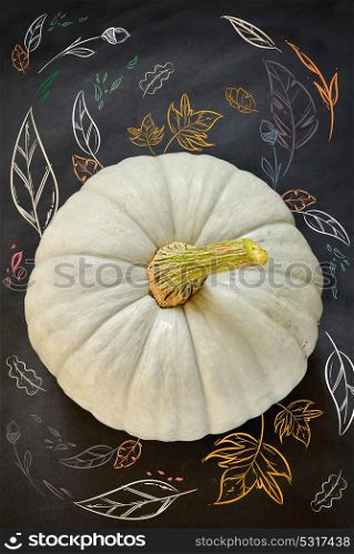Pumpkin with drawn fall foliage on black table