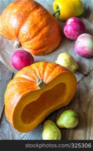 Pumpkin with fruits on the wooden background