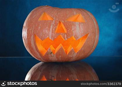 pumpkin with lighting candle inside on blue background