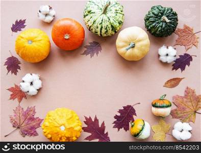 Pumpkins  and fall leaves on a light brown background. Pumpkin harvest. Seasonal vegetables. Flat lay. 