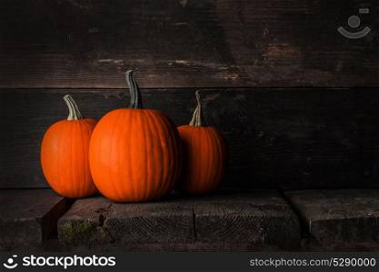 Pumpkins on wooden background. Three orange pumpkins on dark wooden background, Halloween concept