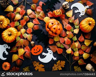 Pumpkins with Halloween decorations on dark background - overhead view flat lay