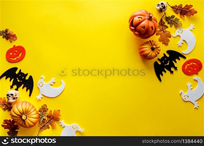 Pumpkins with Halloween decorations on yellow background - overhead view flat lay copyspace