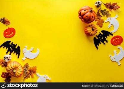 Pumpkins with Halloween decorations on yellow background - overhead view flat lay copyspace