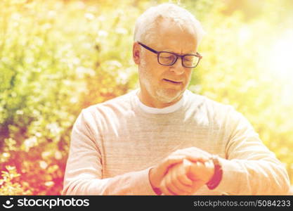 punctuality and people concept - senior man checking time on his wristwatch or smartwatch in city. senior man checking time on his wristwatch. senior man checking time on his wristwatch