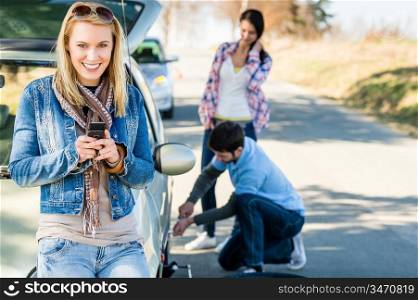 Puncture wheel man changing tire help two female friends