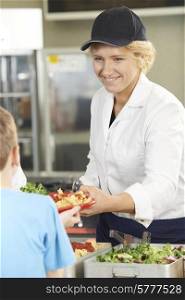 Pupil In School Cafeteria Being Served Lunch By Dinner Lady