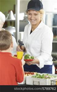 Pupil In School Cafeteria Being Served Lunch By Dinner Lady