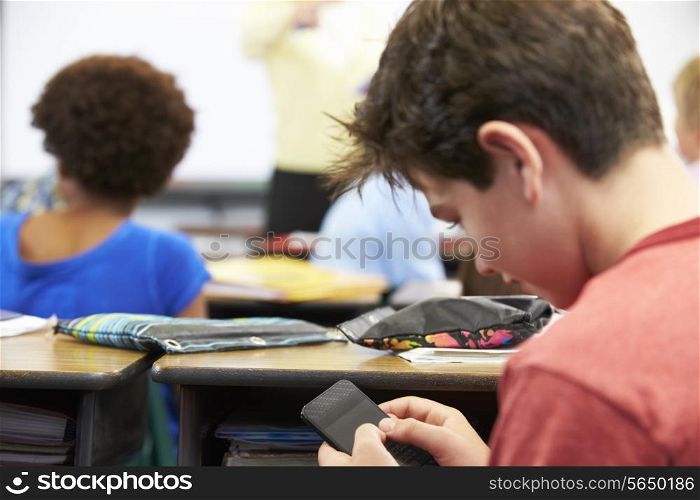 Pupil Sending Text Message On Mobile Phone In Class