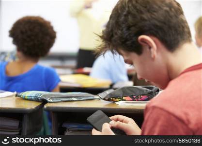 Pupil Sending Text Message On Mobile Phone In Class