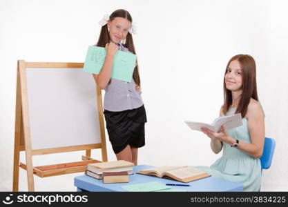 Pupil stands at the blackboard, the teacher sits at his desk and listens to the student