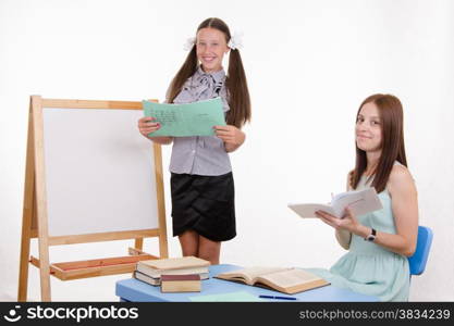 Pupil stands at the blackboard, the teacher sits at his desk and listens to the student