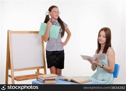 Pupil stands at the blackboard, the teacher sits at his desk and listens to the student