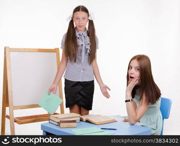 Pupil stands at the blackboard, the teacher sits at his desk and listens to the student