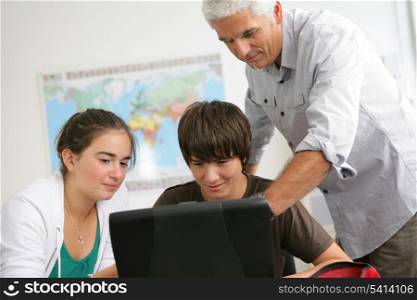 pupils with a teacher behind a laptop