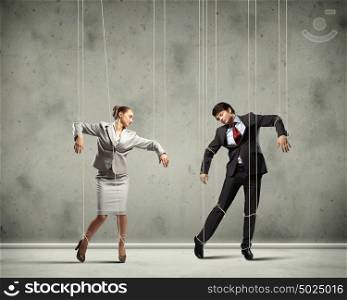 Puppet businesspeople. Image of businesspeople hanging on strings like marionettes. Conceptual photography