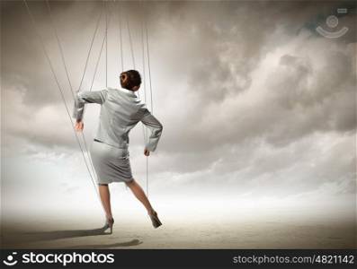 Puppet businesswoman. Image of businesswoman hanging on strings like marionette. Conceptual photography