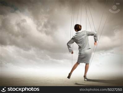 Puppet businesswoman. Image of businesswoman hanging on strings like marionette. Conceptual photography