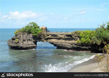 Pura Batu Bolong on the edge of a cliff at coastline with hole in the rock in Bali, Indonesia