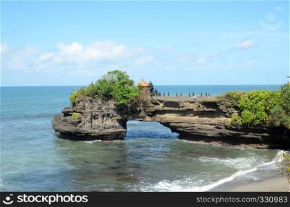 Pura Batu Bolong on the edge of a cliff at coastline with hole in the rock in Bali, Indonesia
