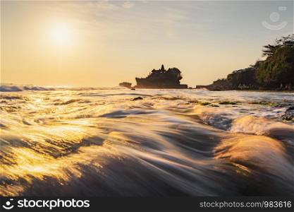 Pura Tanah Lot, the water temple, in Bali at sunset. It is one of the most popular of tourist attraction. Indonesia. Nature landscape background of travel trip and holidays vacation in Indonesia.