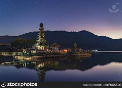 Pura Ulun Danu Bratan Temple, a Hindu temple at night with mountain, lake, and stars, in Bali island, Indonesia. Natural landscape background.