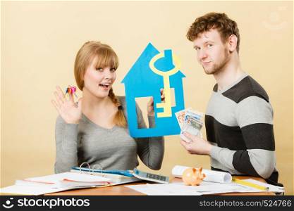 Purchase and construction investment. Just married lovely couple with model of their new home house. Woman and man with key to flat apartment and cash money.. Just married buying house.