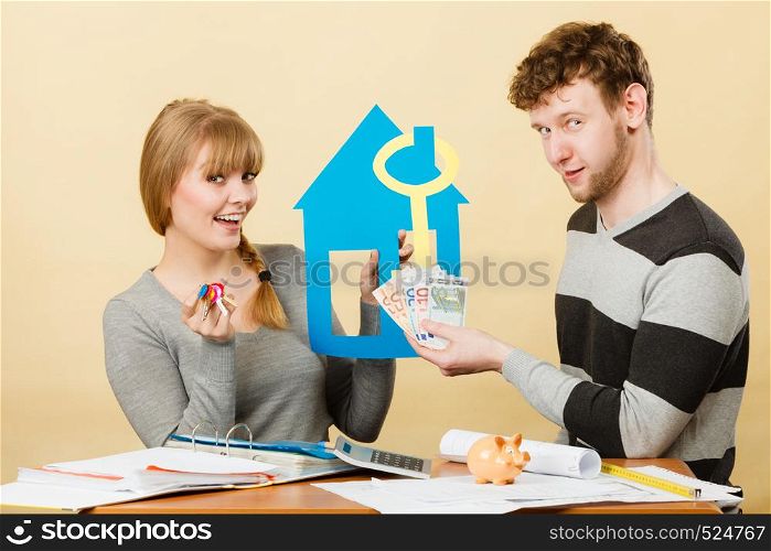 Purchase and construction investment. Just married lovely couple with model of their new home house. Woman and man with key to flat apartment and cash money.. Just married buying house.
